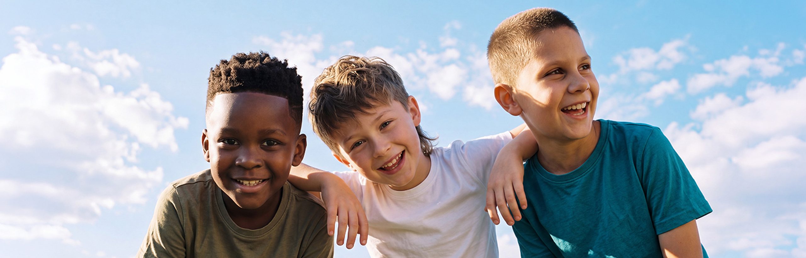 Three smiling boys with varied hairstyles