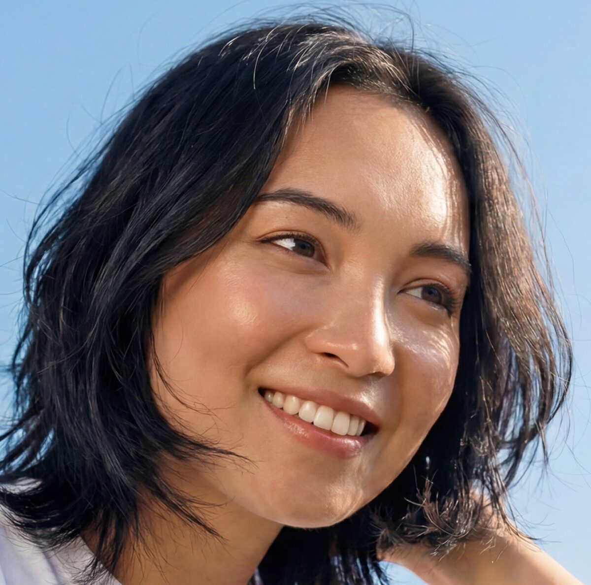 Woman with short layered haircut with her hands in her hair.
