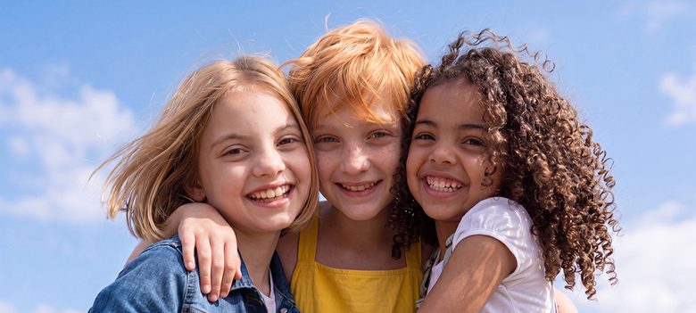 Three smiling girls with varied hairstyles