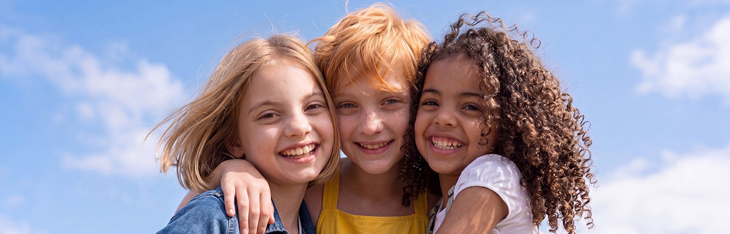 Three smiling girls with varied hairstyles
