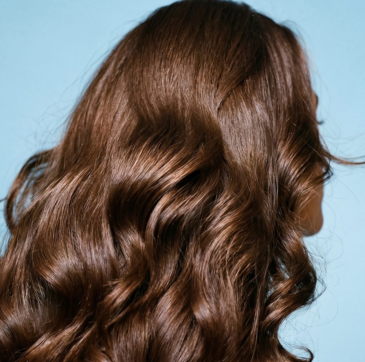 Woman with long, dark, and shiny hair shows Olaplex treatment results