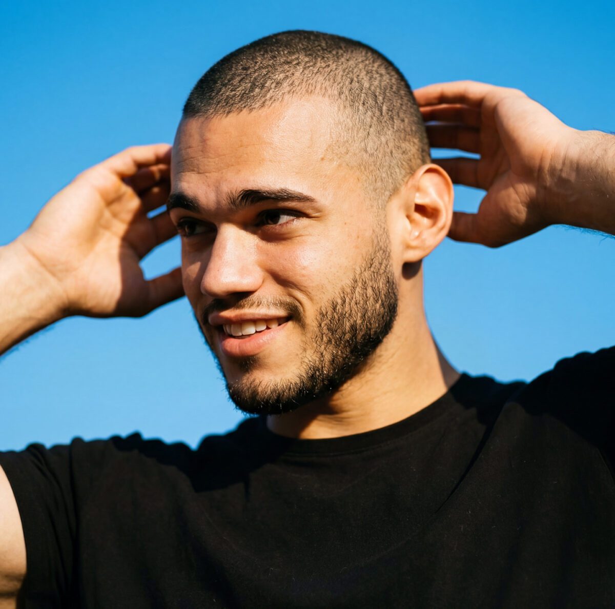 Young man with a buzz cut smiles at the camera.